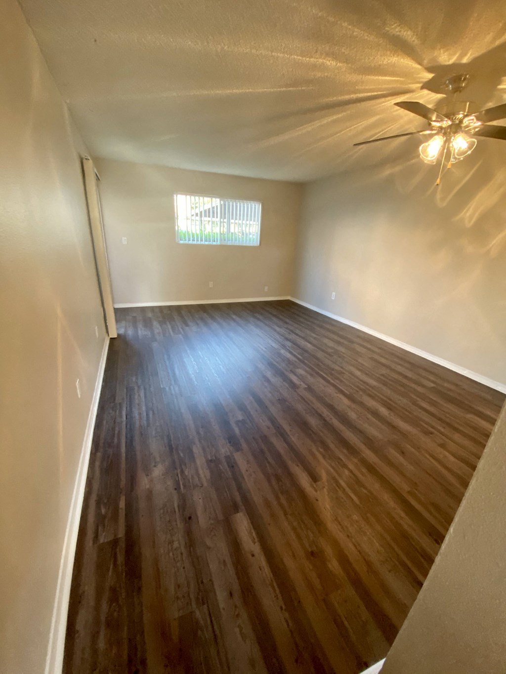 Plank style flooring in living room and dining area with ceiling fan at Villa Pacific Apartments in Oceanside, California.