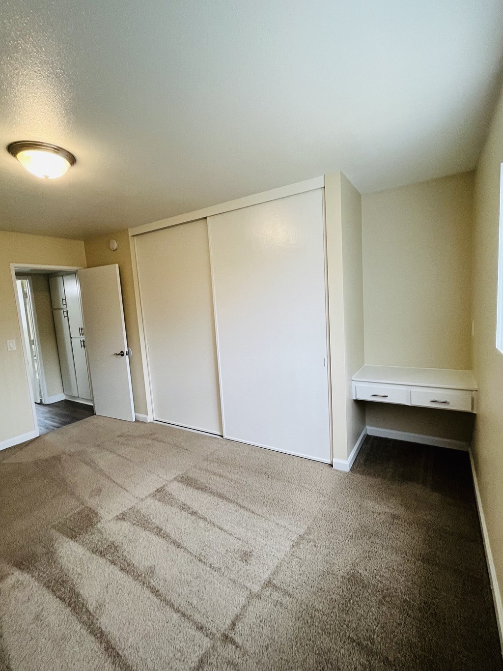 Carpeted bedroom with large closet and build in desk at Plaza Verde Apartments in Escondido, California.