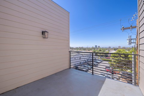 A balcony with a metal railing and a wall with a light switch.