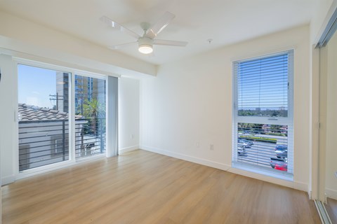 A room with a ceiling fan and sliding glass doors.
