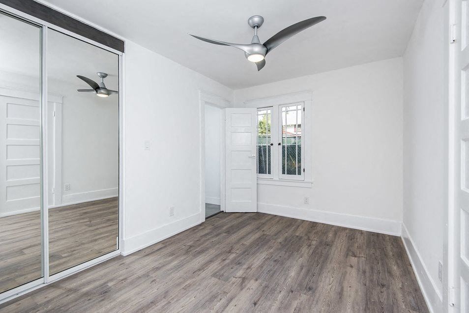 Bedroom with ceiling fan, wood plank style flooring, larage closet with mirrored doors,  and great windows at 4141 Normal Avenue in Los Angeles, California.