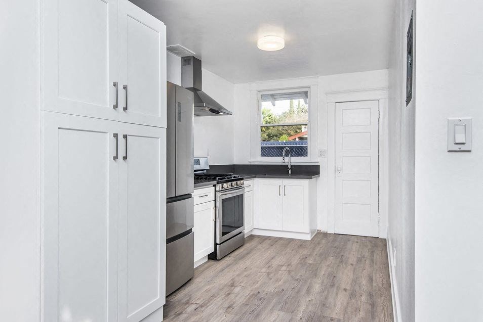 Kitchen with spacious cabinets, gas range, large refridgerator, and back door at 4141 Normal Avenue in Los Angeles, California.