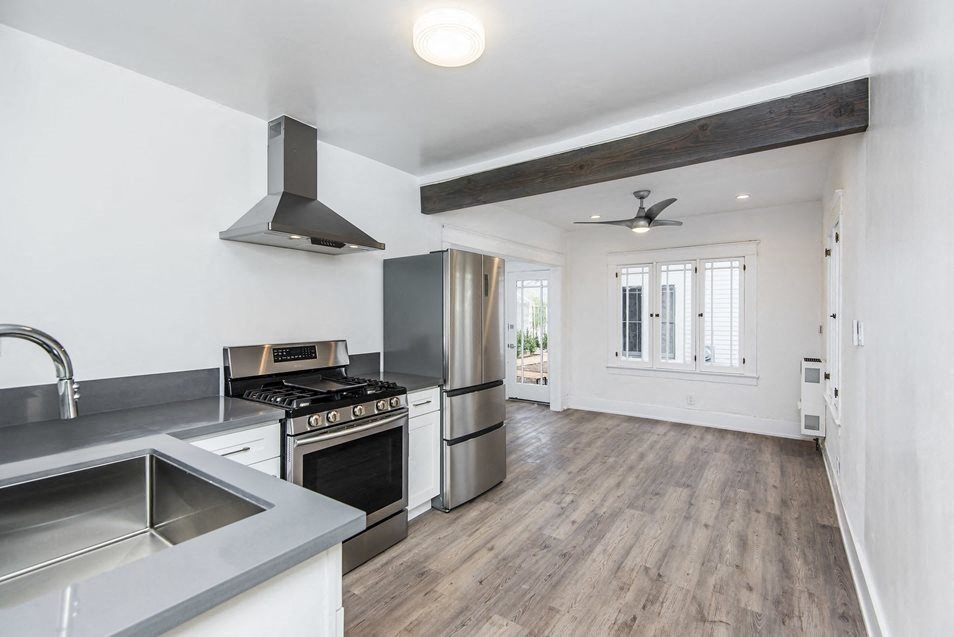 Spacious kitchen looking into dining room area with ceiling fan at 4141 Normal Avenue apartment homes in Los Angeles, California.