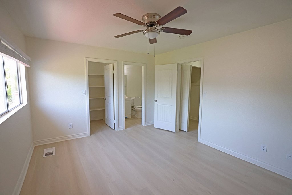 Second large bedroom with hardwood flooring, ceiling fan, private full bathroom, and walk-in closet at Lone Pine Townhomes.
