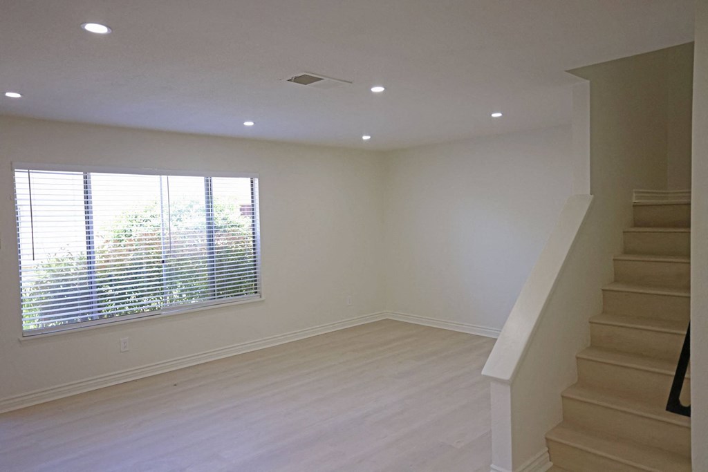 Large front room with garden view, hardwood flooring, privacy blinds, and lots of natural light at Lone Pine Townhomes.