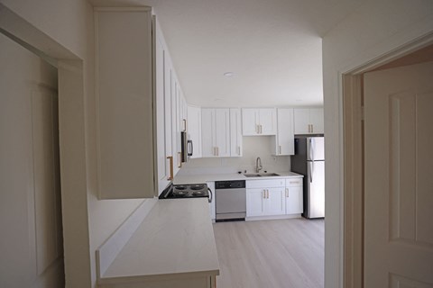 a view of a kitchen with white cabinets and white appliances