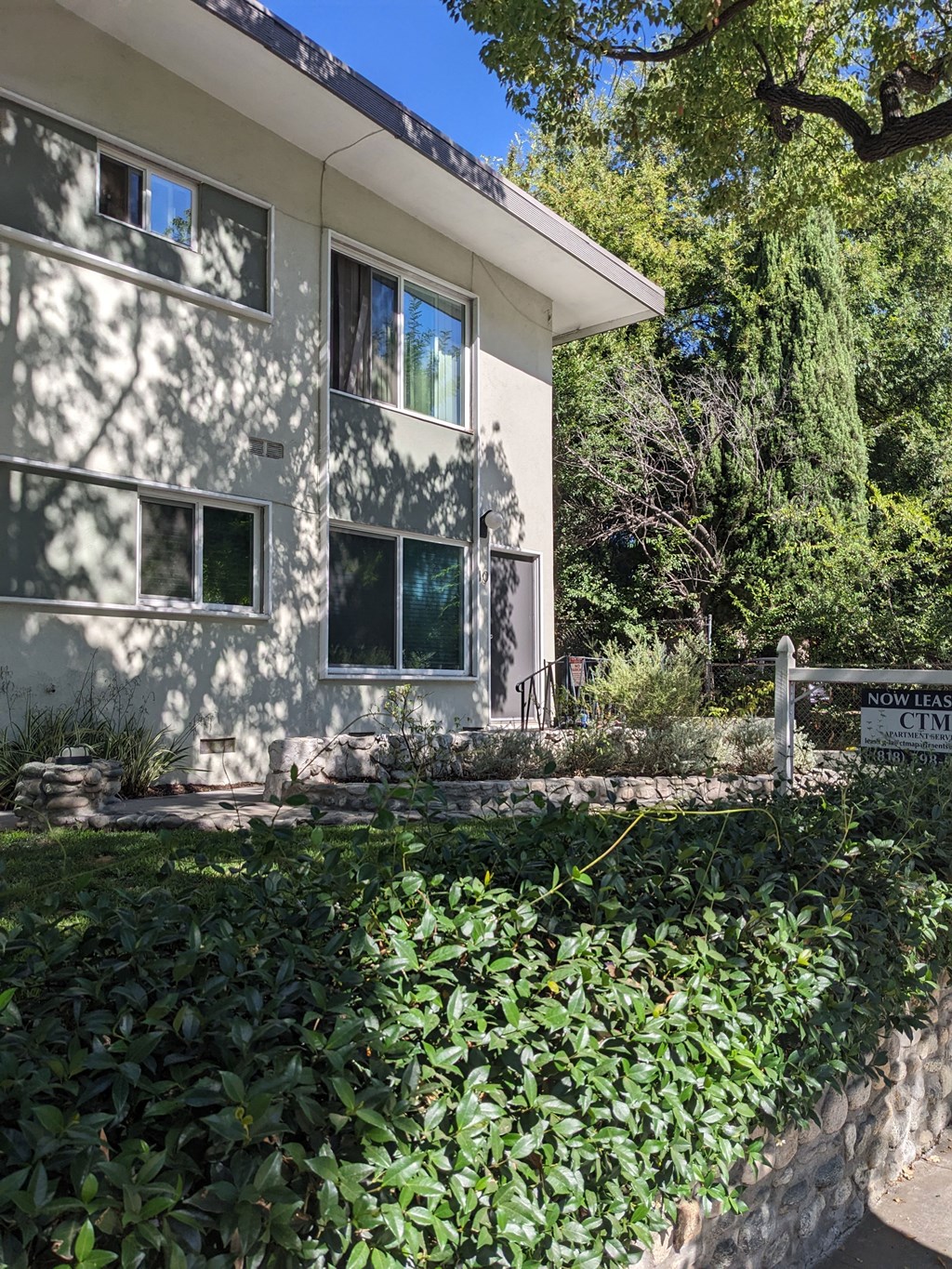 Stone walls and lush gardens and mature trees at Los Robles Apartments in Pasadena, California.