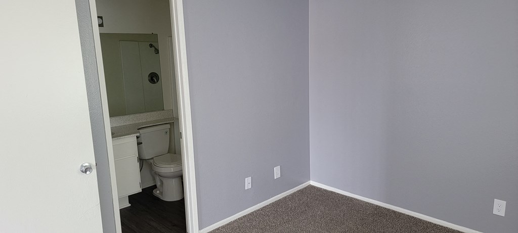 Bedroom with private bathroom at Grand Oaks Apartments in Lake Elsinore, California.