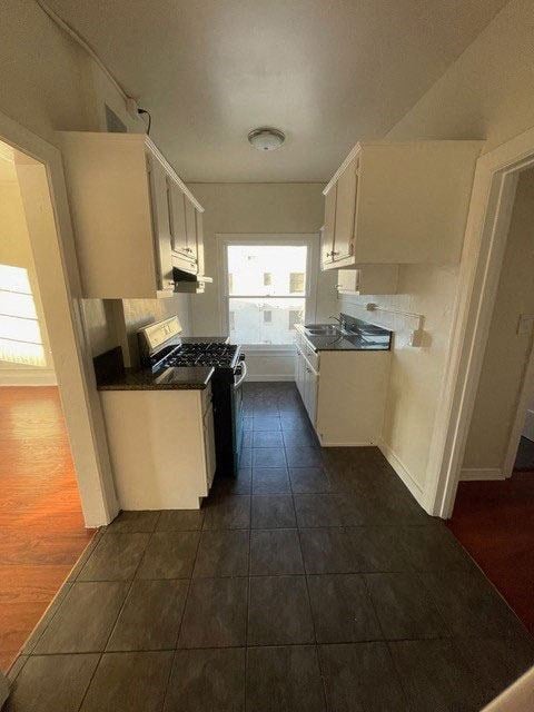 Kitchen with white cabinets and gas range in apartment unit of Molinio Del Mar Apartments in Pasadena, California.