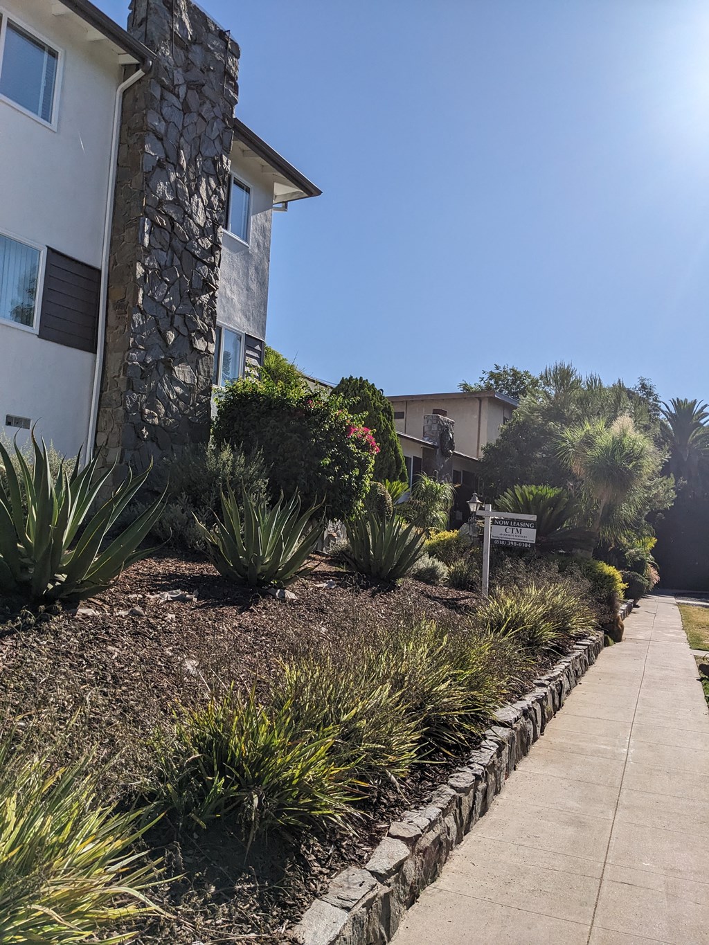 Sidewalk view of front yard landscaping at The Hardison Apartments in Pasadena, California.