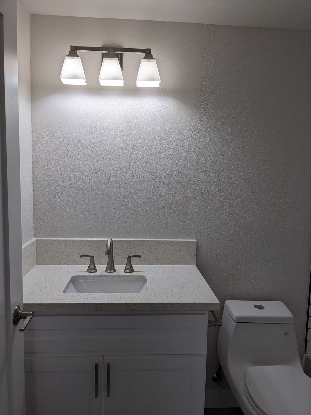 Lots of bathroom lighting and white fixtures at The Hardison Apartments in Pasadena, California.