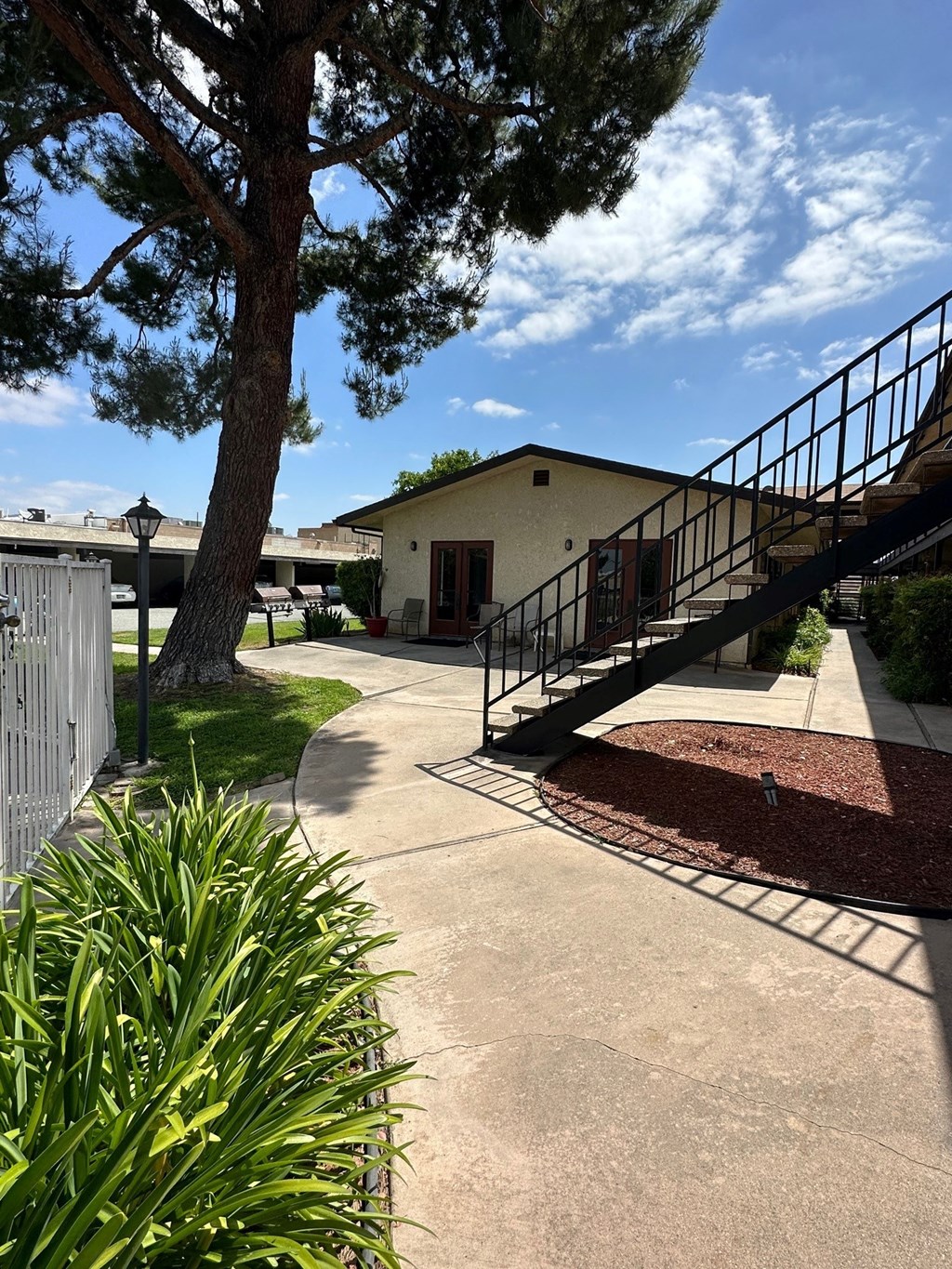 Mature trees and gardens along building walkways at Park Yale Apartments in Hemet, California.