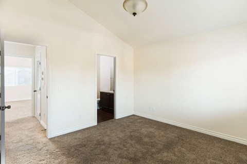 Large carpeted bedrooms with shared bathroom and cathedral ceilings at The Nines Townhomes in Escondido, California.