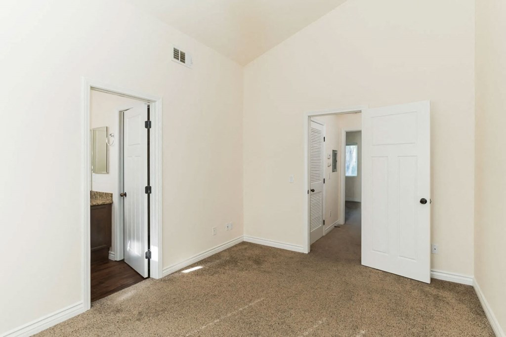 Carpeted bedroom with cathedral ceinling and bathroom at The Nines Townhomes in Escondido, California.
