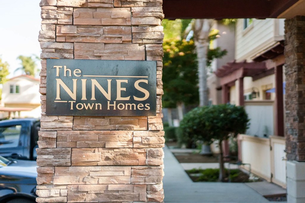Stone column with The Niines Town Homes sign near front enterance in Escondido, California.