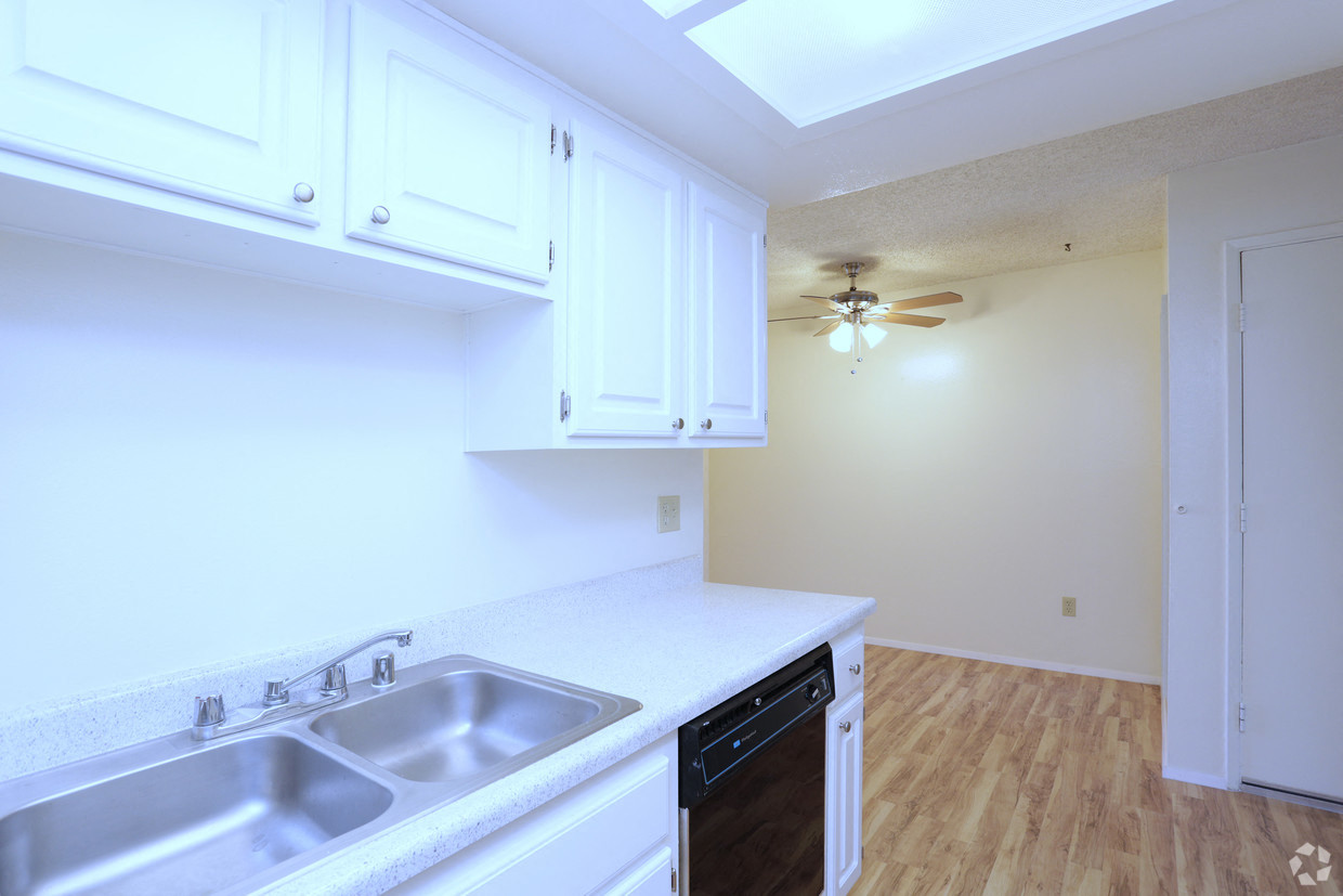 a kitchen with white cabinets and a sink and a ceiling fan