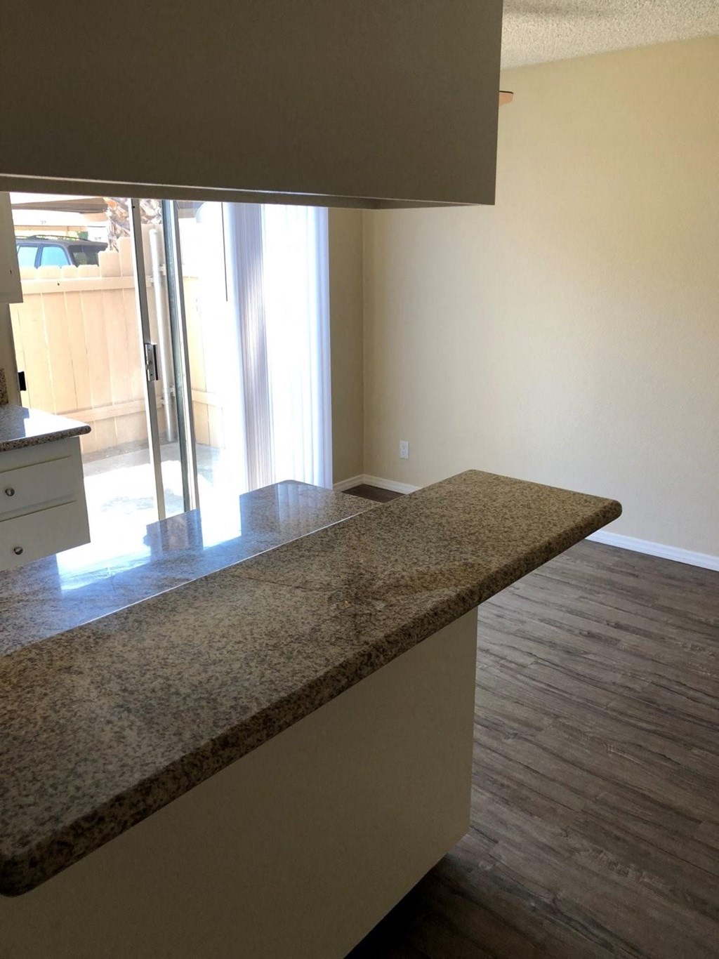 View of kitchen serving bar and dining area with sliding glass door to private porch at Plaza Verde Apartments in Escondido, California.
