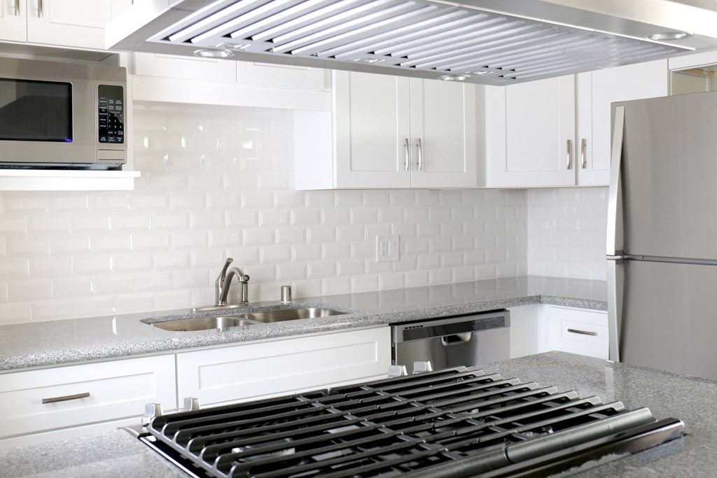 Kitchen with gas range, microwave, dishwasher, and refrigerator at Harbor Villa Apartments in San Diego, California.