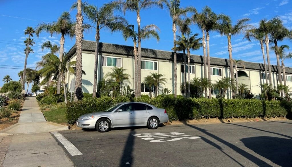 Beautiful blue sky and stately palm trees surround Saint Malo Surf Apartments in Oceanside, California.