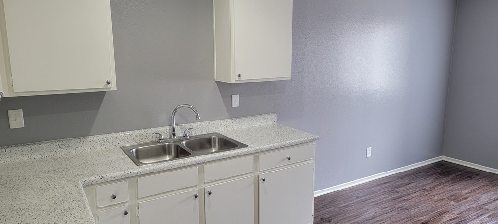 Kitchen with spacious white cabinets and large eating area at Grand Oaks Apartments in Lake Elsinore, California.