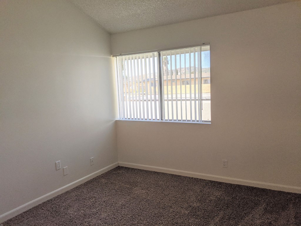 Carpeted bedroom with great natural light in apartment unit at the Steckel Apartments in Santa Paula, California.