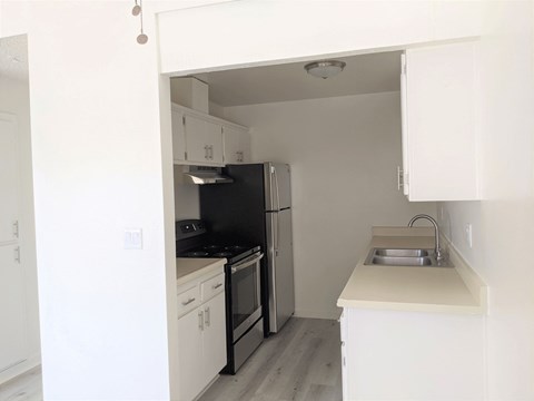 an empty kitchen with white cabinets and a black refrigerator
