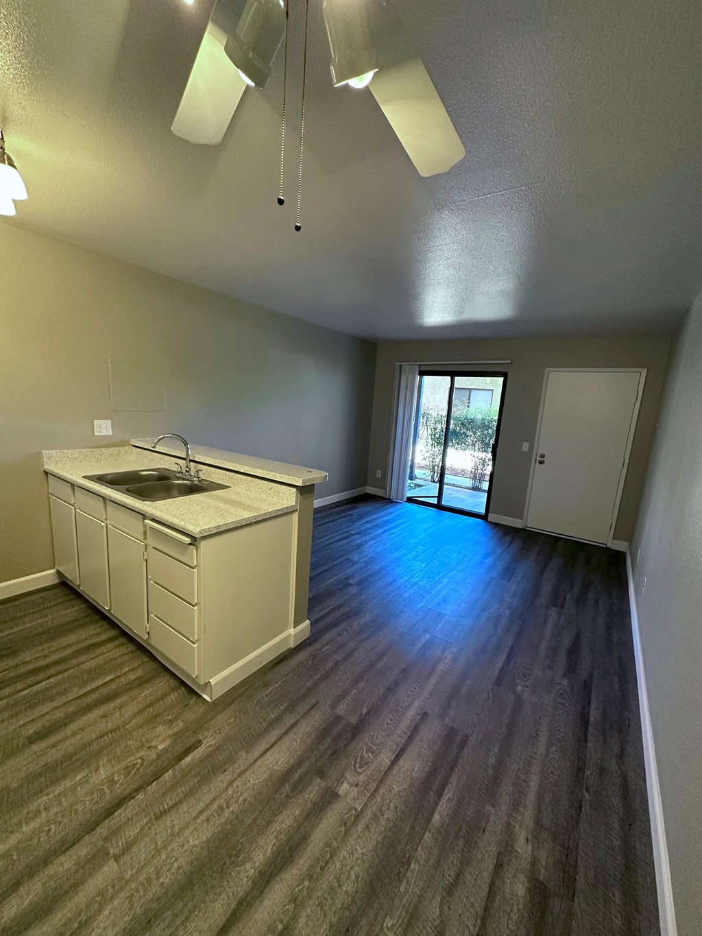 Open floor plan with kitchen, dining area and living room featuring plank style flooring at Park Yale Apartments in Hemet, California.