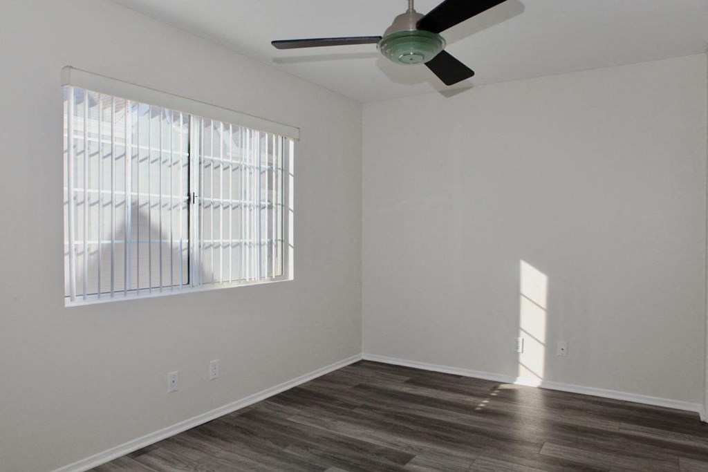 Bedroom with lots of natural light and ceiling fan in unit at Summer House Apartments in Ventura, California.