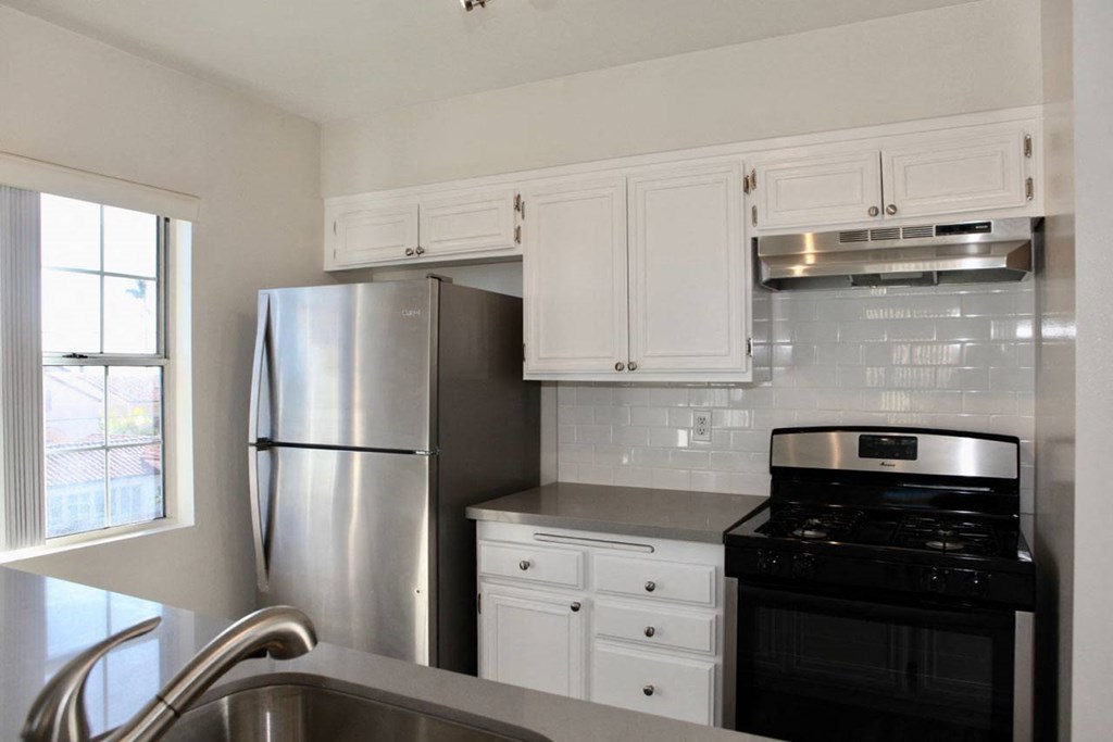 Kitchen with lots of natural light and spaciaou white cabinets in apartment at Summer House in Ventura, California.