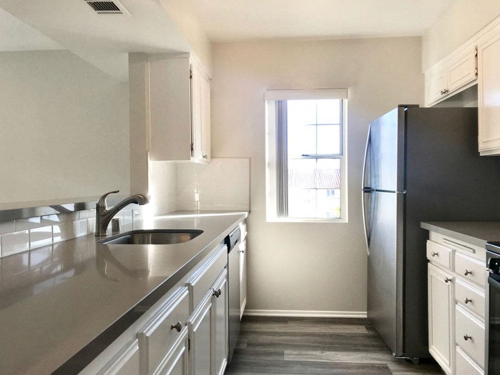Open kitchen with lots of counter space and white cabinets in unit at Summer House Apartments in Ventura, California.