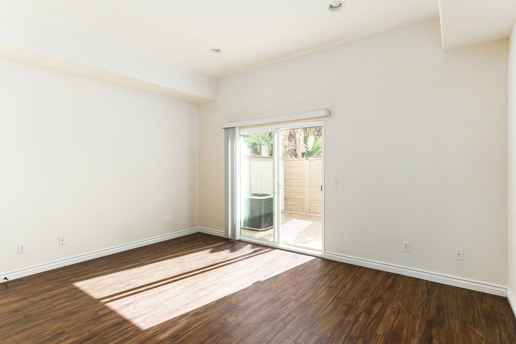 Living room with wood style laminate floors and sliding glass doors to private porch at The Nines Townhomes in Escondido, California.