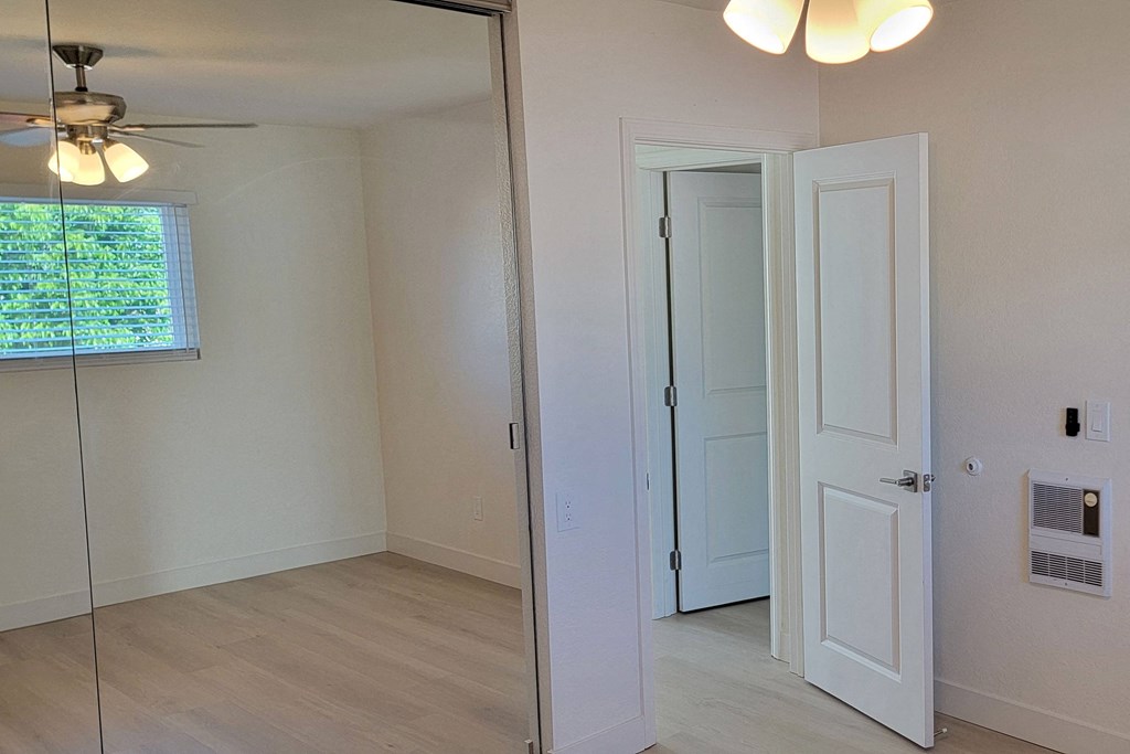 Bedroom one with large closets and ceiling fan in unit 17 at The Willows at Washington apartments in El Cajon, California.