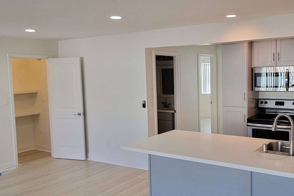 View of kitchen, bedroom hallway, and front room with large closet in unit 21 at The Willows at Washington apartments in El Cajon, California.