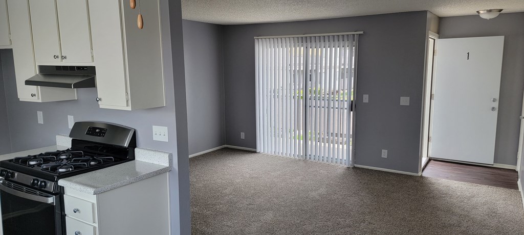 Enterance, carpeted living room and kitchen at Grand Oaks Apartments in Lake Elsinore, California.