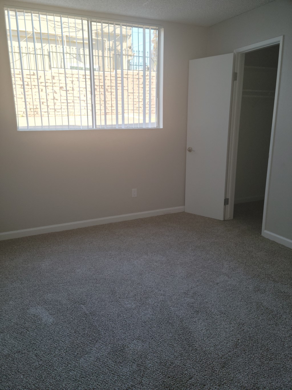 Bedroom with a large window at La Mesa Village Apartments in La Mesa, California..