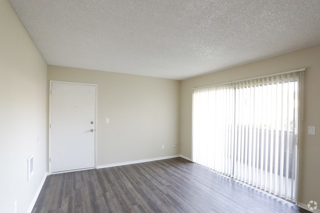 Living room with front door and sliding glass doors to private porch at Villa Pacific Apartments in Oceanside, California.