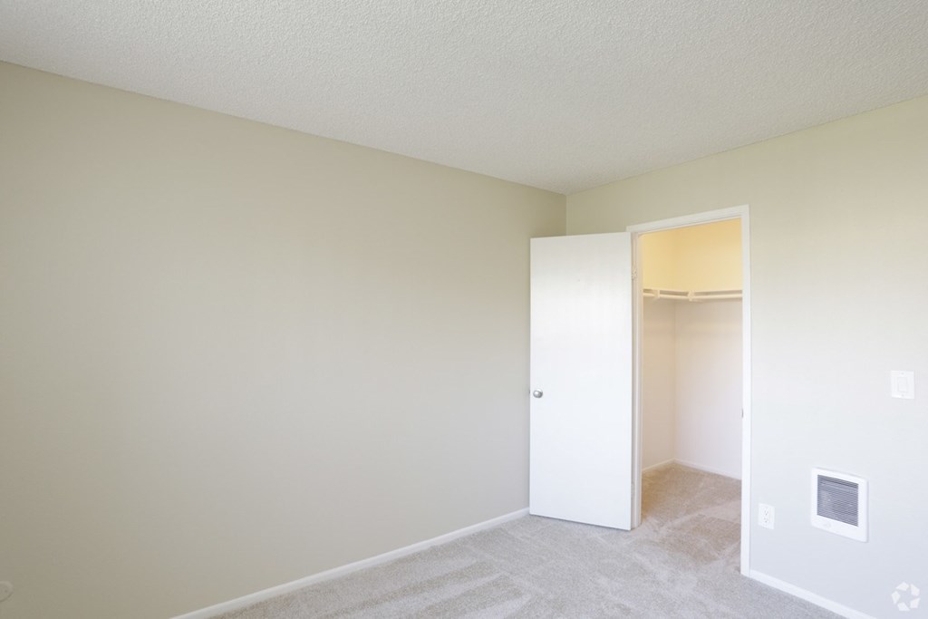 Carpeted bedroom with walk-in closet at Villa Pacific Apartments in Oceanside, California.