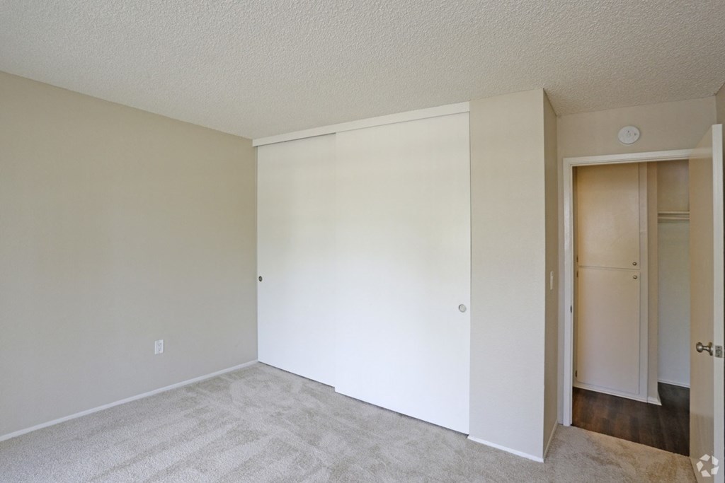 Carpeted bedroom with large closet at Villa Pacific Apartments in Oceanside, California.
