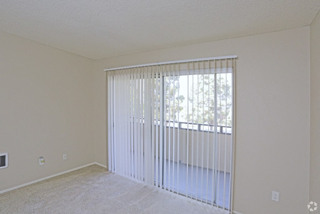 Carpeted master bedroom with sliding glass door to private porch at Villa Pacific Apartments in Oceanside, California.