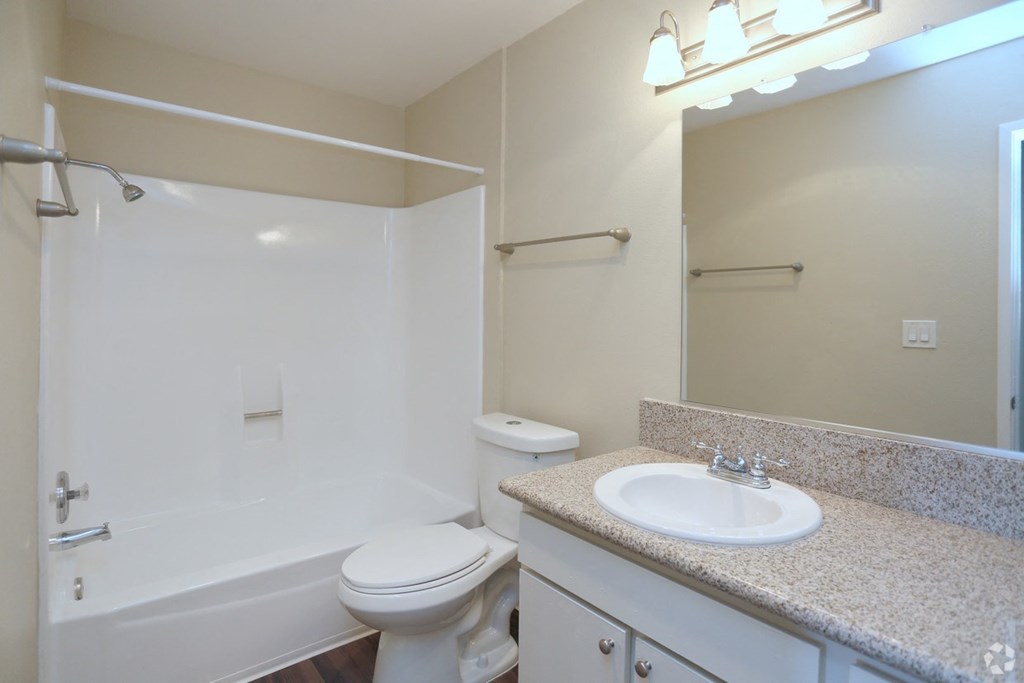 Bathroom with white fixtures and vanity with white cabinets in unit at Villa Pacific Apartments in Oceanside, California.