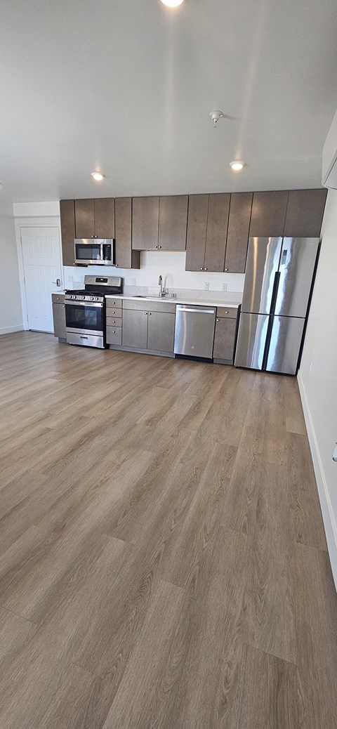 A modern kitchen with wooden floors and a large mirror on the wall.