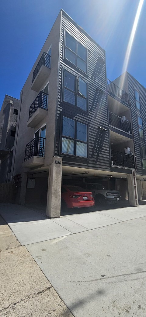 A tall building with a red car parked on the side.
