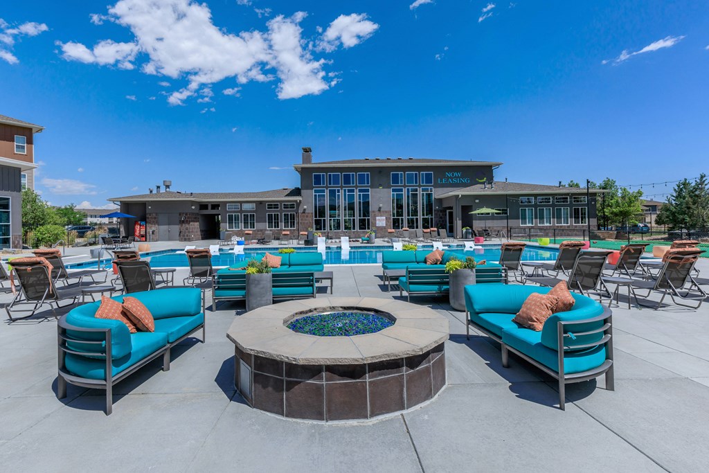 A patio with blue couches and a fire pit in front of a building.