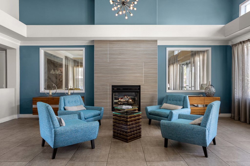 a living room with blue chairs and a fireplace
