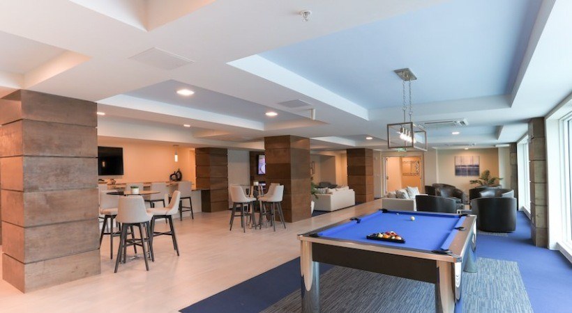 A well-lit room with a pool table and a bar area.