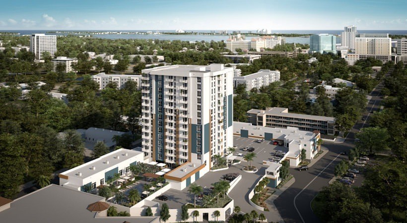 A modern multi-story building with a parking lot in front.