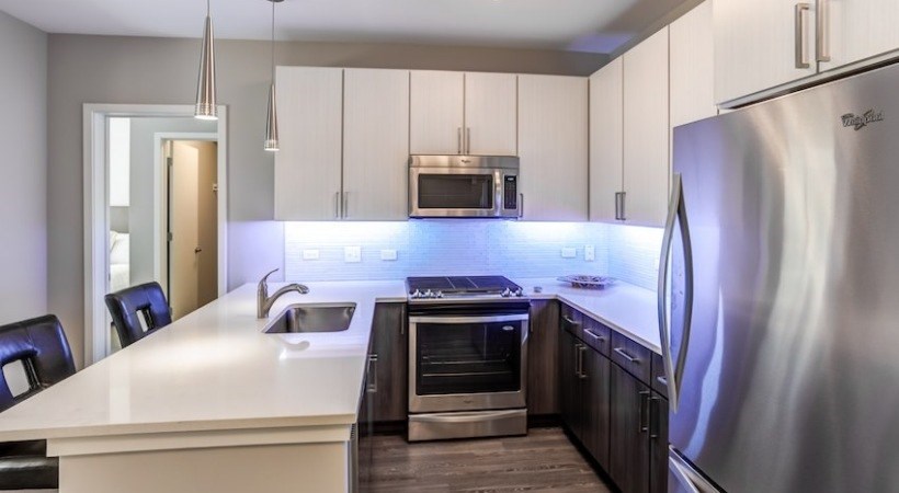 A modern kitchen with a stainless steel refrigerator and a built-in oven.