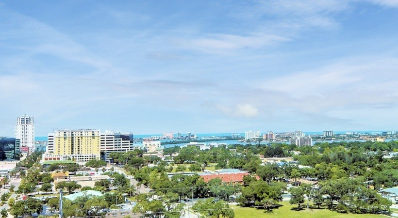 A cityscape with a large building in the center and a body of water in the distance.