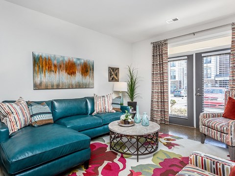 a living room with a blue couch and a rug    and a door