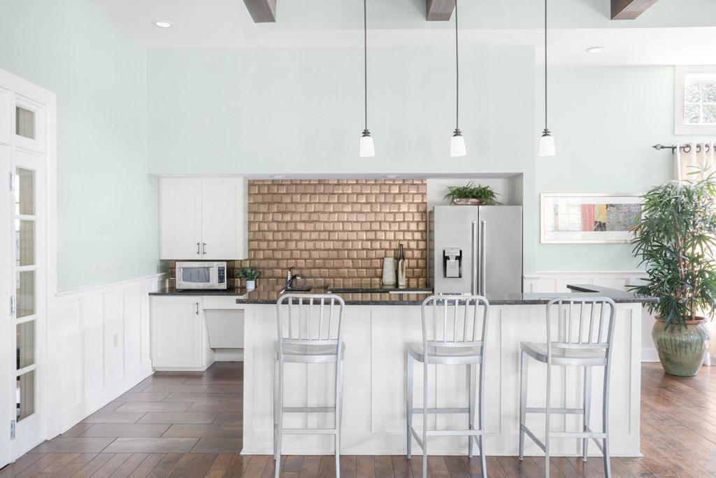 a kitchen with white cabinets and a white island with stools